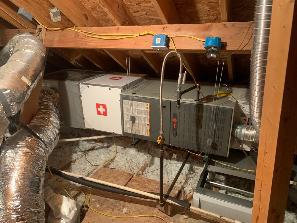 HVAC system installed in attic with insulation and ductwork visible.