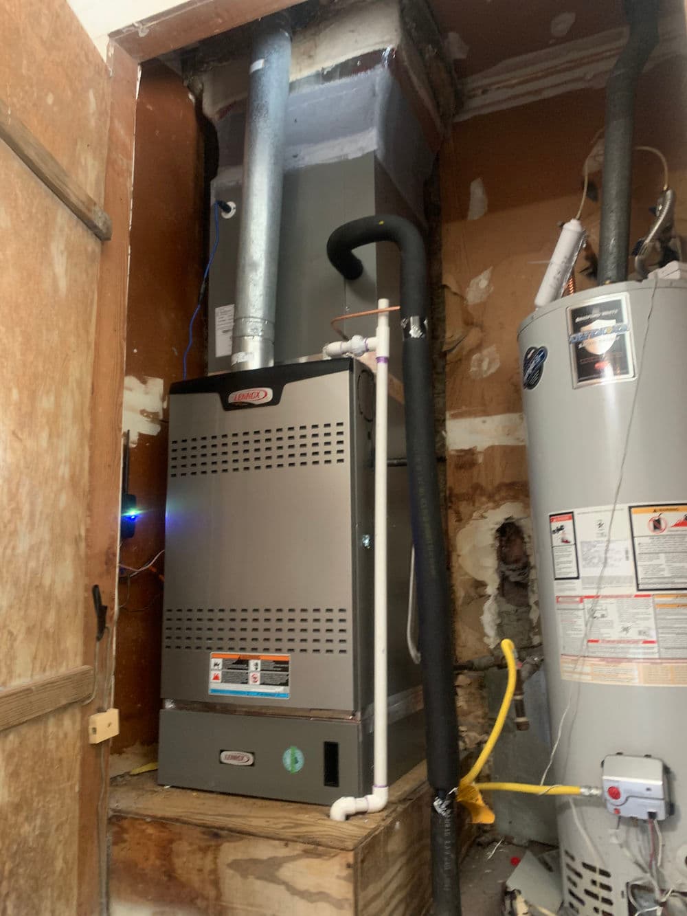 Residential furnace installation in utility room with water heater and piping.